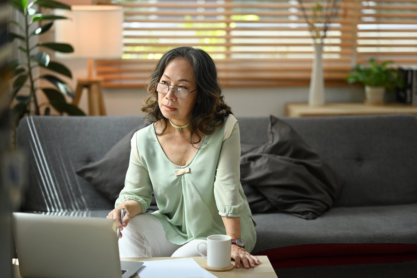 Mature woman reading news online, checking social media on laptop computer.